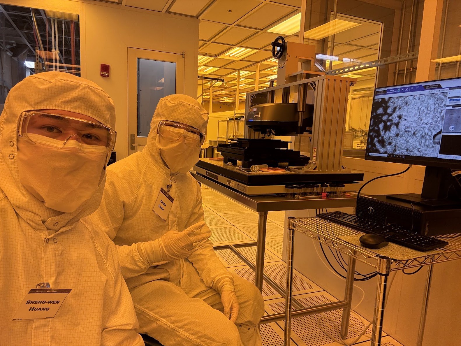 Owen Chen and a colleague in cleanroom PPE beside semiconductor imaging equipment